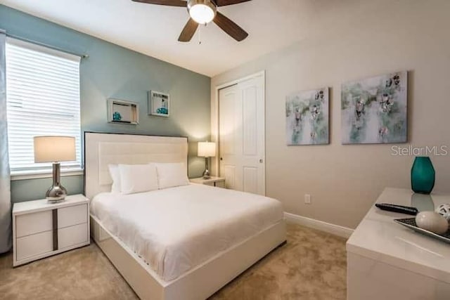 carpeted bedroom featuring multiple windows, ceiling fan, and a closet