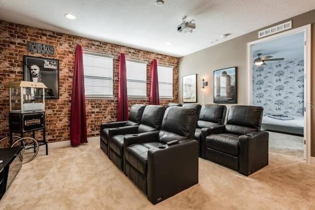 home theater room with light carpet, a textured ceiling, brick wall, and ceiling fan