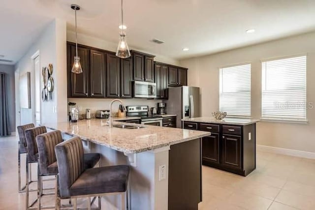 kitchen with appliances with stainless steel finishes, a breakfast bar area, sink, and decorative light fixtures