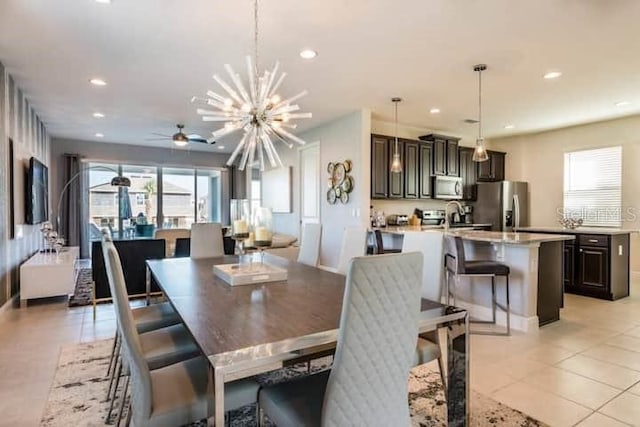 tiled dining space featuring sink and ceiling fan with notable chandelier