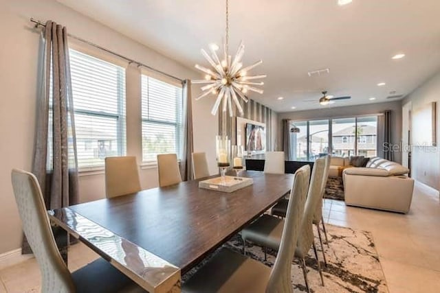 dining space with ceiling fan with notable chandelier, a wealth of natural light, and light tile patterned flooring