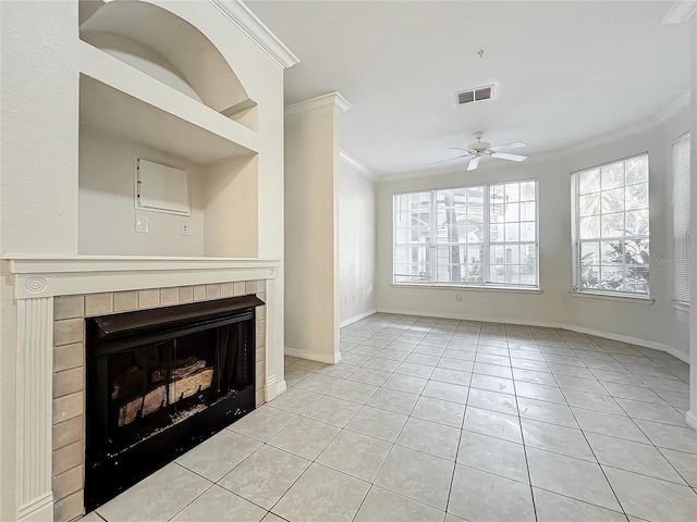 unfurnished living room with a tiled fireplace, crown molding, light tile patterned floors, and ceiling fan