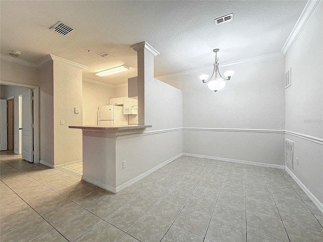 empty room with a textured ceiling, ornamental molding, light tile patterned floors, and a notable chandelier