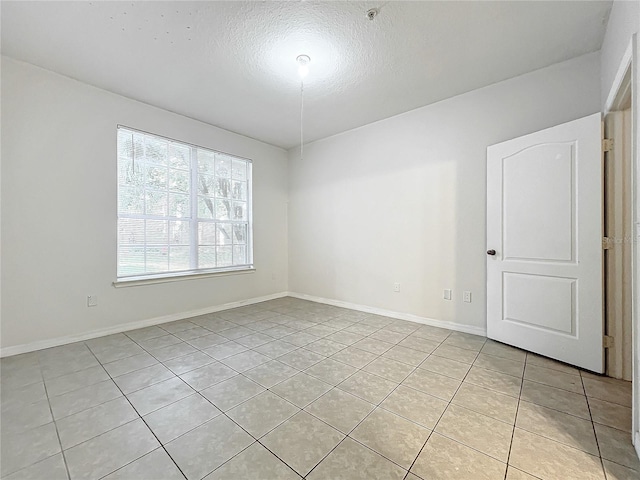 tiled empty room with a textured ceiling