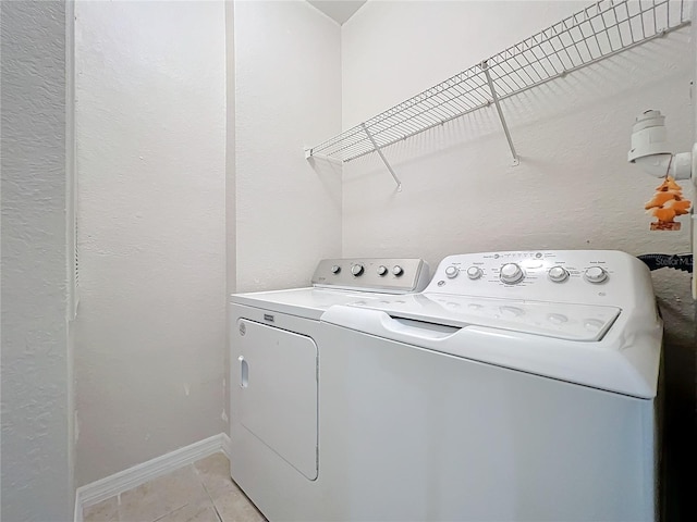 laundry area with independent washer and dryer and light tile patterned floors