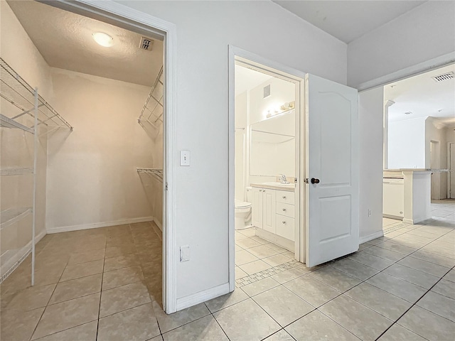 spacious closet with light tile patterned floors and sink