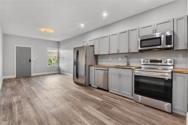 701 N Grandview Ave, Daytona Beach, FL 32118 - kitchen featuring appliances with stainless steel finishes, butcher block countertops, a sink, gray cabinetry, and light wood finished floors