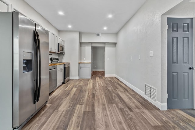 kitchen with hardwood / wood-style flooring, stainless steel appliances, and wooden counters