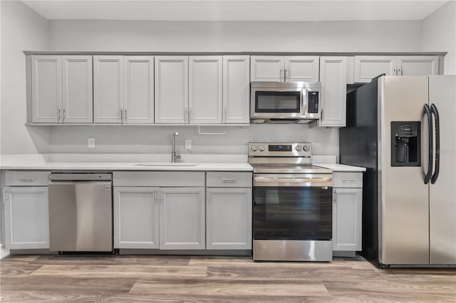 kitchen featuring appliances with stainless steel finishes, sink, and light hardwood / wood-style floors