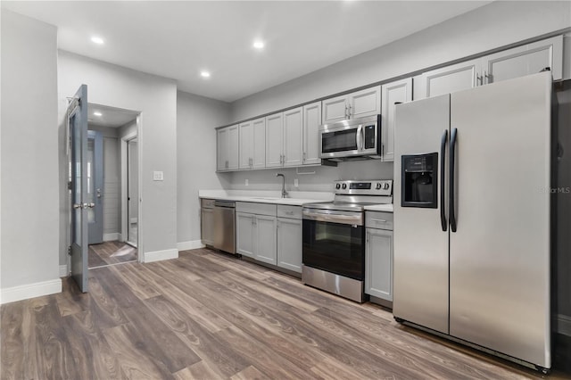 kitchen featuring gray cabinets, hardwood / wood-style floors, appliances with stainless steel finishes, and sink