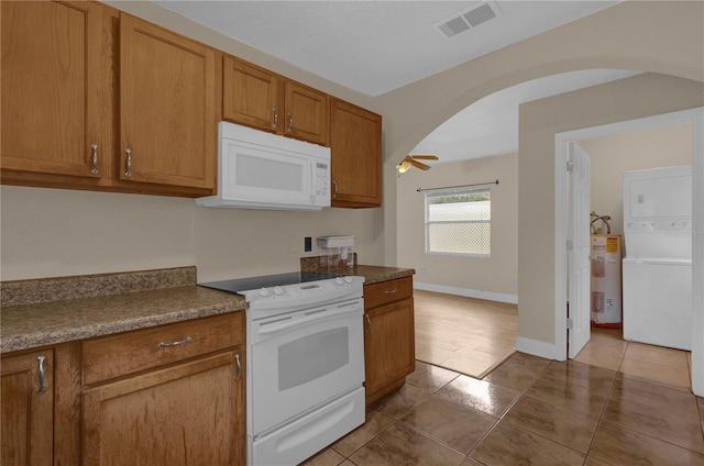 kitchen with stacked washer and dryer, tile patterned floors, electric water heater, white appliances, and ceiling fan