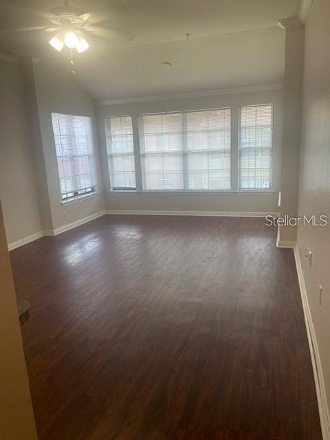 empty room featuring dark wood-type flooring, a healthy amount of sunlight, and ceiling fan