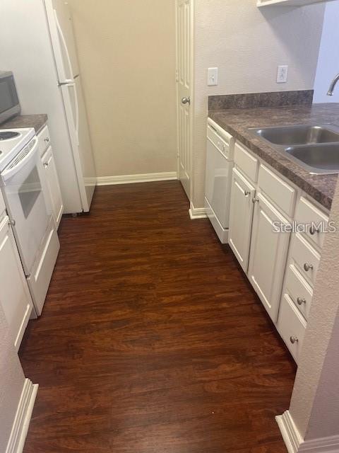 kitchen featuring dark hardwood / wood-style floors, sink, white appliances, and white cabinetry