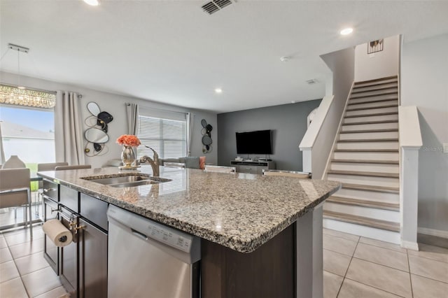 kitchen featuring light tile patterned floors, dishwasher, light stone counters, sink, and a kitchen island with sink