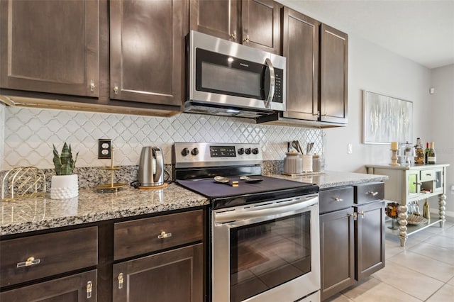 kitchen featuring light stone countertops, light tile patterned floors, backsplash, stainless steel appliances, and dark brown cabinetry