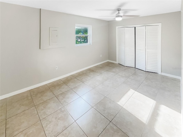 unfurnished bedroom with a closet, light tile patterned floors, a ceiling fan, and baseboards