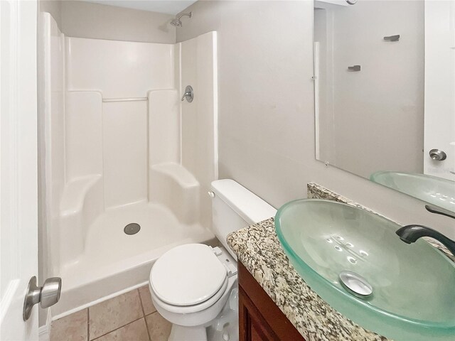 bathroom featuring tile patterned flooring, vanity, toilet, and walk in shower