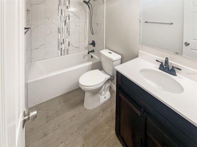 full bathroom with toilet, tiled shower / bath combo, hardwood / wood-style flooring, and vanity