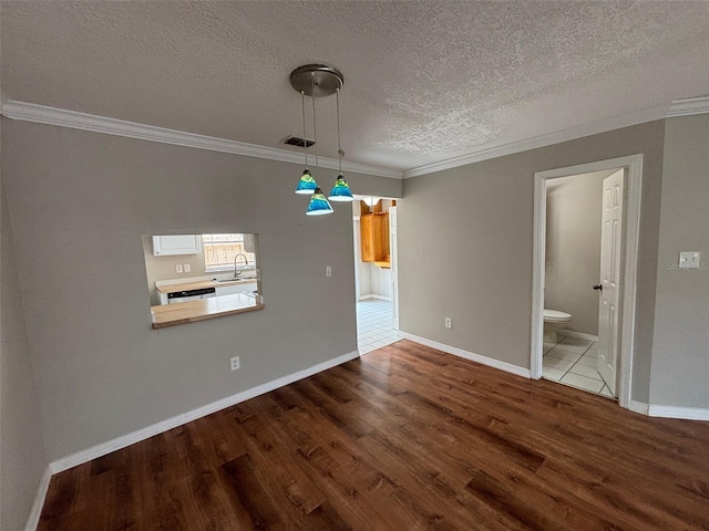 unfurnished dining area with crown molding, a textured ceiling, hardwood / wood-style floors, and sink