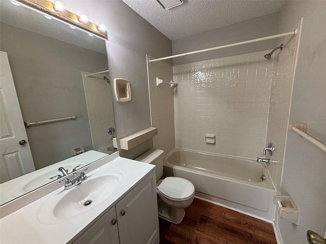 full bathroom with hardwood / wood-style floors, toilet, tiled shower / bath combo, vanity, and a textured ceiling