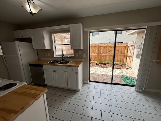 kitchen featuring white fridge, white cabinetry, light tile patterned floors, sink, and stainless steel dishwasher