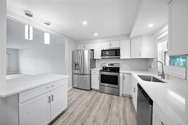 kitchen with light wood-type flooring, light stone counters, stainless steel appliances, white cabinetry, and sink