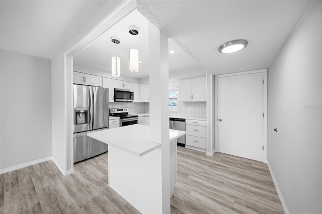 kitchen featuring hanging light fixtures, light wood-type flooring, appliances with stainless steel finishes, and white cabinets