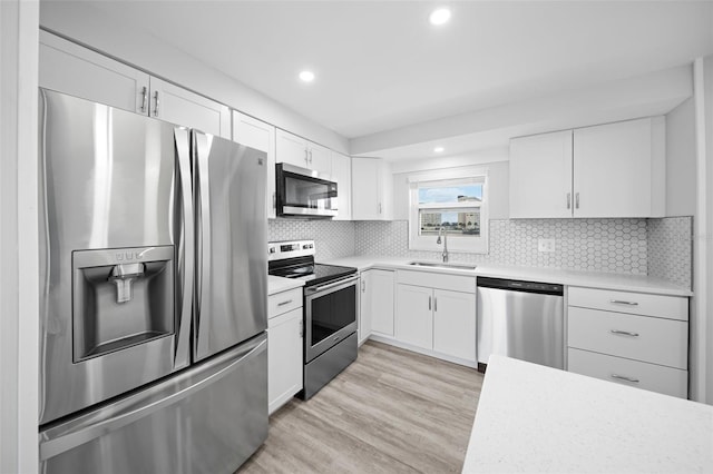 kitchen with light hardwood / wood-style flooring, sink, appliances with stainless steel finishes, and white cabinets