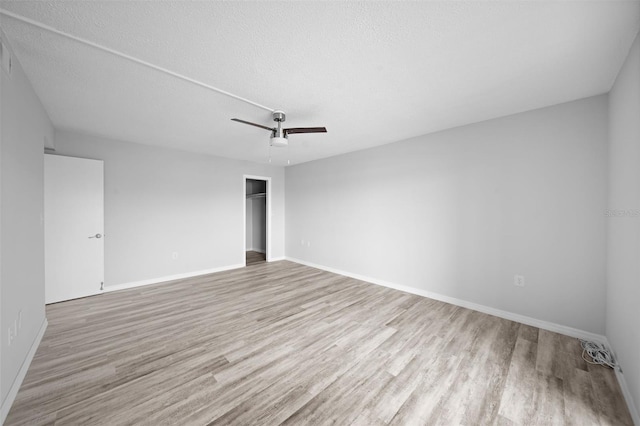 unfurnished room with a textured ceiling, ceiling fan, and light wood-type flooring