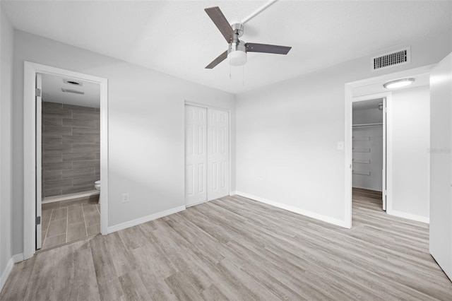 unfurnished bedroom with light hardwood / wood-style floors, ceiling fan, a closet, and connected bathroom