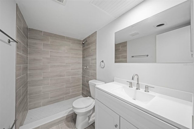 bathroom featuring vanity, toilet, and a tile shower