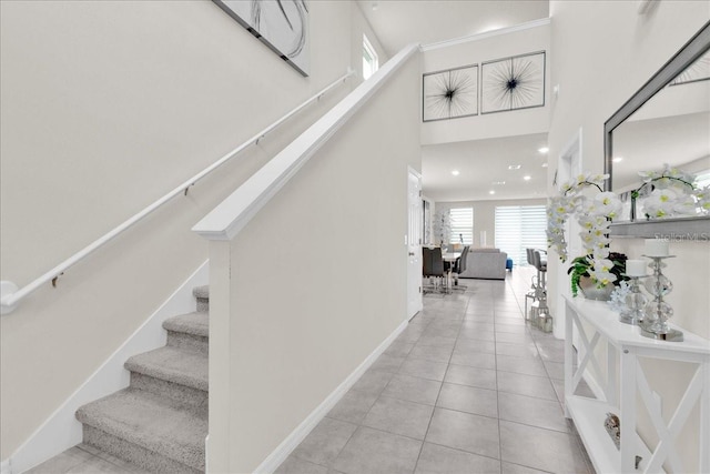 hallway with a towering ceiling and light tile patterned floors