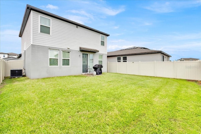 rear view of house featuring central air condition unit and a lawn