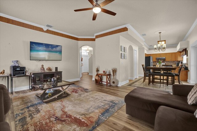 living room featuring ceiling fan with notable chandelier, ornamental molding, and light hardwood / wood-style floors