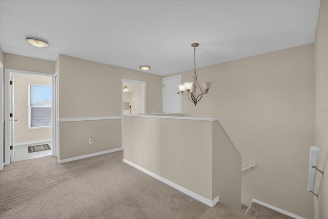 carpeted spare room with an inviting chandelier