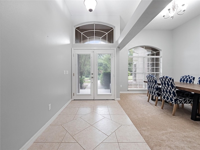 entryway with baseboards, tile patterned flooring, carpet flooring, and an inviting chandelier