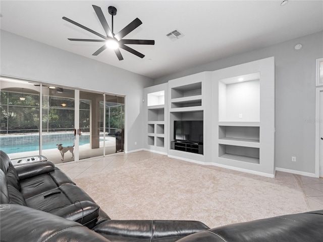 carpeted living room with built in shelves, visible vents, ceiling fan, baseboards, and tile patterned floors