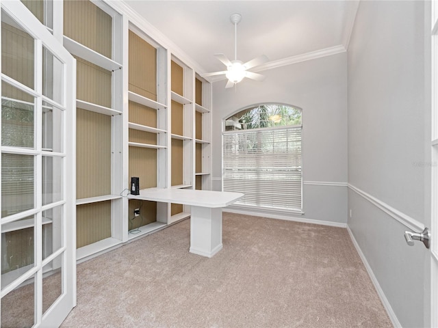 unfurnished office with carpet floors, baseboards, a ceiling fan, and ornamental molding