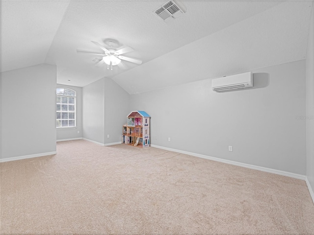 additional living space with a wall unit AC, vaulted ceiling, visible vents, and baseboards