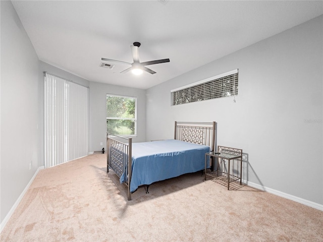 carpeted bedroom featuring a ceiling fan, visible vents, and baseboards