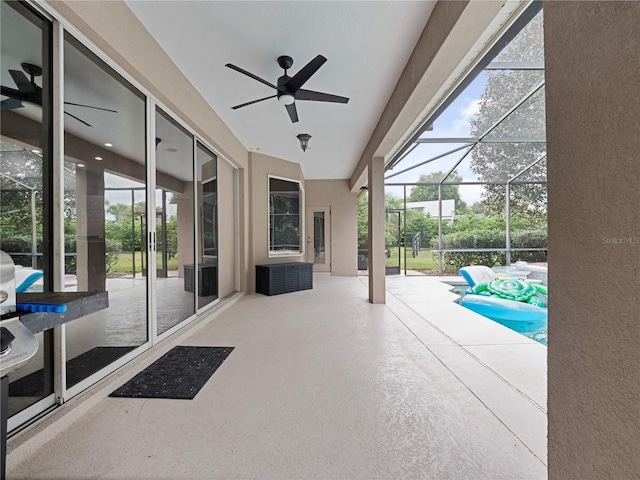 view of patio featuring a ceiling fan, glass enclosure, and a swimming pool