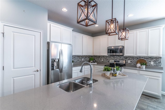 kitchen with tasteful backsplash, light stone counters, stainless steel appliances, white cabinetry, and a sink