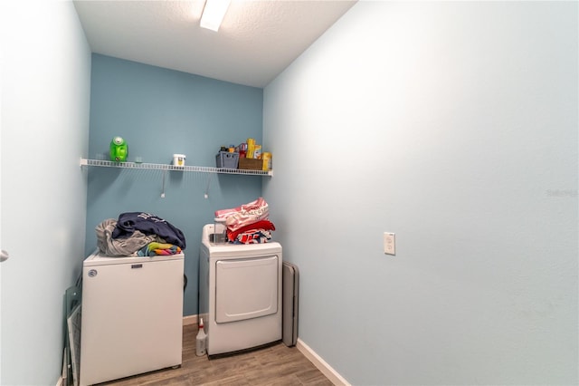 washroom featuring a textured ceiling, laundry area, wood finished floors, baseboards, and independent washer and dryer