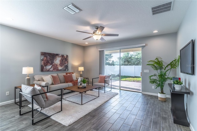 living room featuring ceiling fan, dark hardwood / wood-style floors, and a textured ceiling