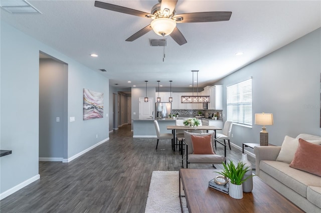 living area featuring dark wood-type flooring, visible vents, and baseboards