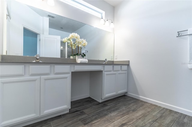 bathroom with double vanity, visible vents, a sink, wood finished floors, and baseboards