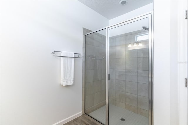 bathroom featuring a stall shower, wood finished floors, and baseboards