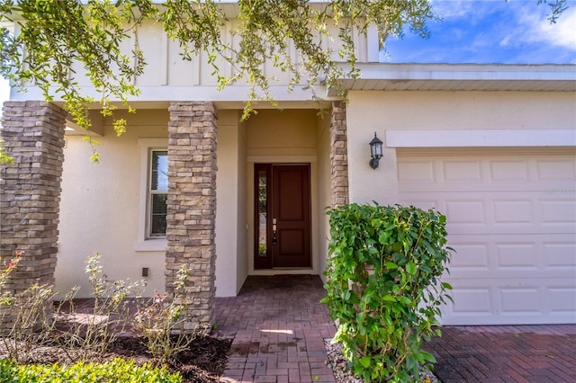 doorway to property with an attached garage and stucco siding