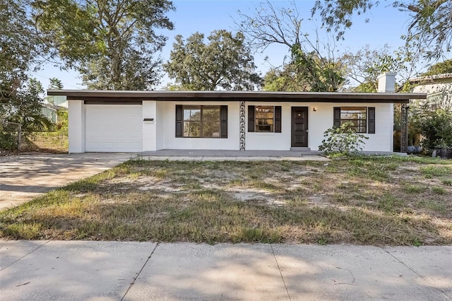 ranch-style home featuring a chimney, concrete driveway, and an attached garage