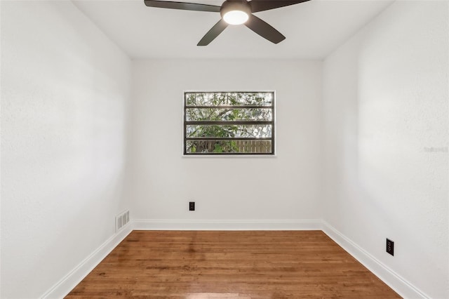 unfurnished room featuring a ceiling fan, visible vents, wood finished floors, and baseboards